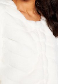 Hvid fluffy jakke med quiltet design og blød tekstur, med synlige sømme og rundet halsudskæring, velegnet til afslappet brug.