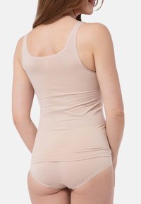 Light beige tank top made of soft material with a fitted design. Features wide straps and a smooth texture. Paired with matching beige brief.