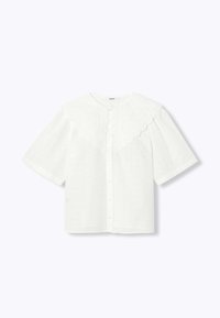 Blouse blanche à manches courtes avec un col festonné, une fermeture à boutons et des détails en broderie anglaise sur l'ensemble du tissu. Texture douce et légère.