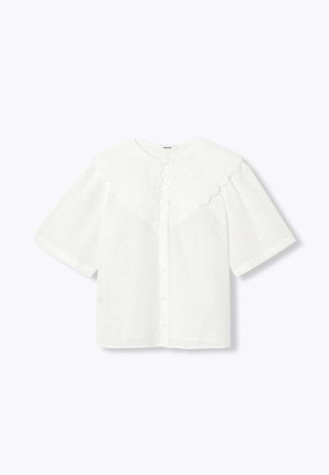 Blouse blanche à manches courtes avec un col festonné, une fermeture à boutons et des détails en broderie anglaise sur l'ensemble du tissu. Texture douce et légère.