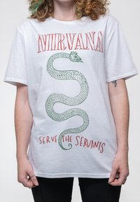 White cotton T-shirt featuring a green serpent graphic, with "NIRVANA" in red above and "SERVE THE SERVANTS" in red below. Short sleeves.