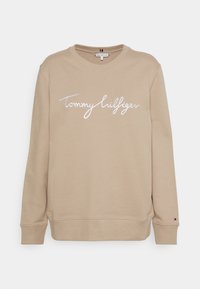 Béžová mikina z měkké bavlněné látky. Obsahuje vyšitý bílý nápis "Tommy Hilfiger". Dlouhé rukávy s žebrovanými manžetami a lemem.