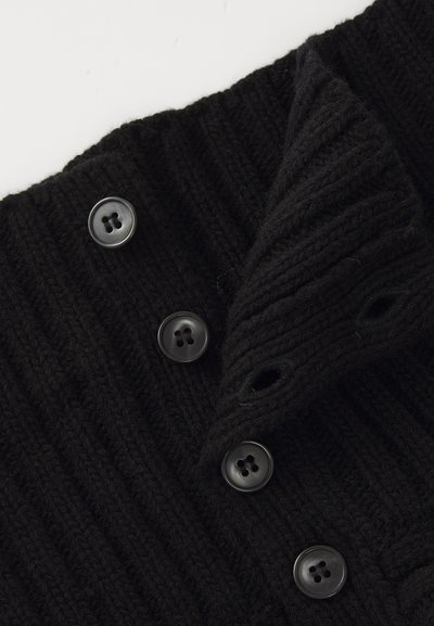 Sort strikket sweaterkrave med ribbet tekstur, seks sorte fire-huls knapper og en overlappende flap med øjekonturer.