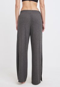 Graue, gerippte, weite Hose mit strukturierter Oberfläche, seitlichen Schlitzen und einem elastischen Bund für Komfort und Bewegungsfreiheit.