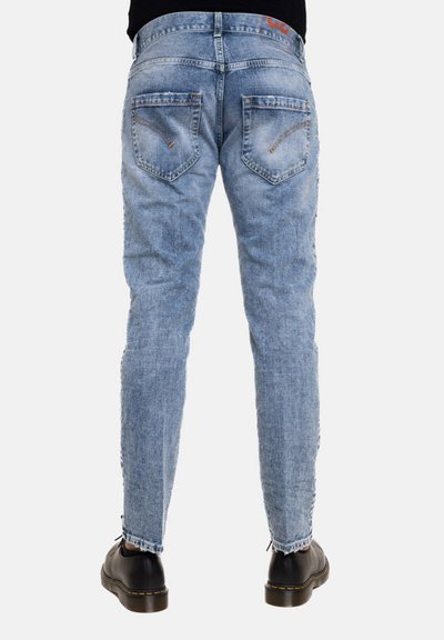 Jeans in denim blu chiaro con taglio slim, dotati di tasche posteriori con cuciture curve e un orlo leggermente sfilacciato. Abbinati a scarpe nere.