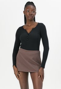 Fekete, hosszú ujjú, bordázott felső gombdísszel, barna mintás, rúdtokruhában; sima textúra és testhez simuló fazon.