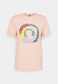 Světle broskvový bavlněný tričko s krátkými rukávy. Obsahuje kruhovou grafiku v různých barvách, včetně červené, zelené a růžové, zobrazující text značky.