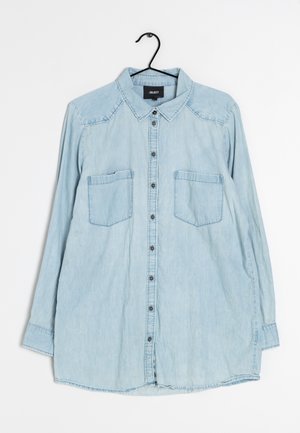 Light blue long-sleeve denim shirt with button front, two chest pockets, and a collar, displayed on a black hanger.