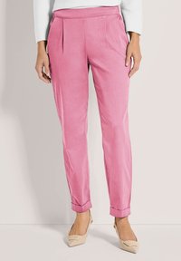 Roze broek met een gladde textuur, voorzien van voorplooien, een aangesloten pasvorm en opgerolde zoom, gecombineerd met nude gekleurde hakken.