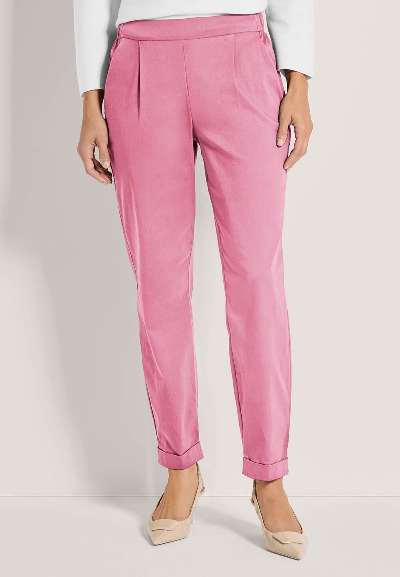 Roze broek met een gladde textuur, voorzien van voorplooien, een aangesloten pasvorm en opgerolde zoom, gecombineerd met nude gekleurde hakken.