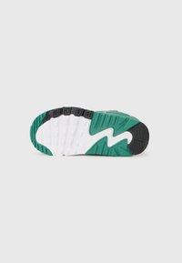 Semelle de chaussure avec un design ondulé ; présente du caoutchouc noir, des accents verts et des sections de semelle intermédiaire blanches. Texturée pour une meilleure adhérence avec un motif de bande de roulement visible.