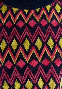 Dzianinowy sweter z geometrycznym wzorem różowych, żółtych i czarnych diamentów na granatowym tle. Prążkowany detal na karku.