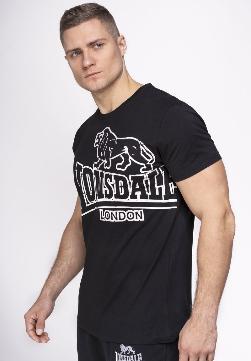 Tricou negru din bumbac cu imprimeu alb "Lonsdale London" și grafică cu leu, mâneci scurte și guler rotund.