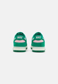 Grüne Wildleder-Sneaker mit rosa Akzenten, ausgestattet mit einem weißen Nike-Logo an der Ferse und einer strukturierten Gummisohle. Abgerundetes Design an der Spitze.