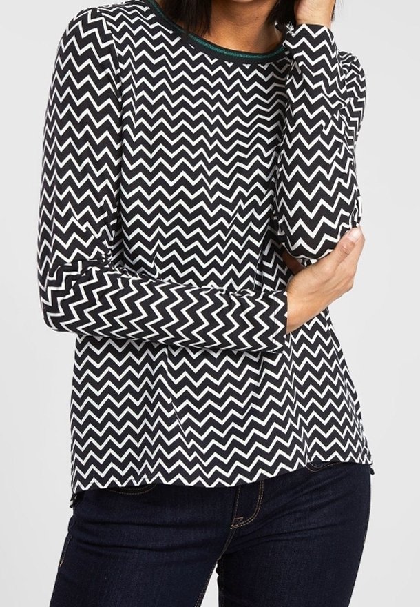 Černobílá košile s chevron vzorem, dlouhý rukáv, kulatý výstřih a kontrastní zelené lemování. Měkká látka a volný střih.