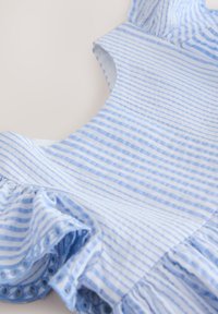 Blue and white striped sleeveless cotton dress with gathered ruffle hem, laid flat on a light surface.