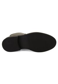 Semelle de chaussure en caoutchouc noir avec une surface texturée, comportant des rainures horizontales pour la traction et une section médiane lisse sans détails.