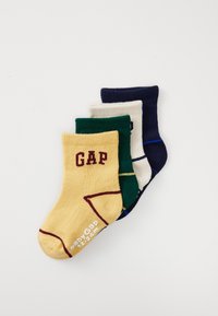 Four folded baby socks in yellow, green, white, and navy, with "GAP" branding and size 12-24 months printed on yellow sock.