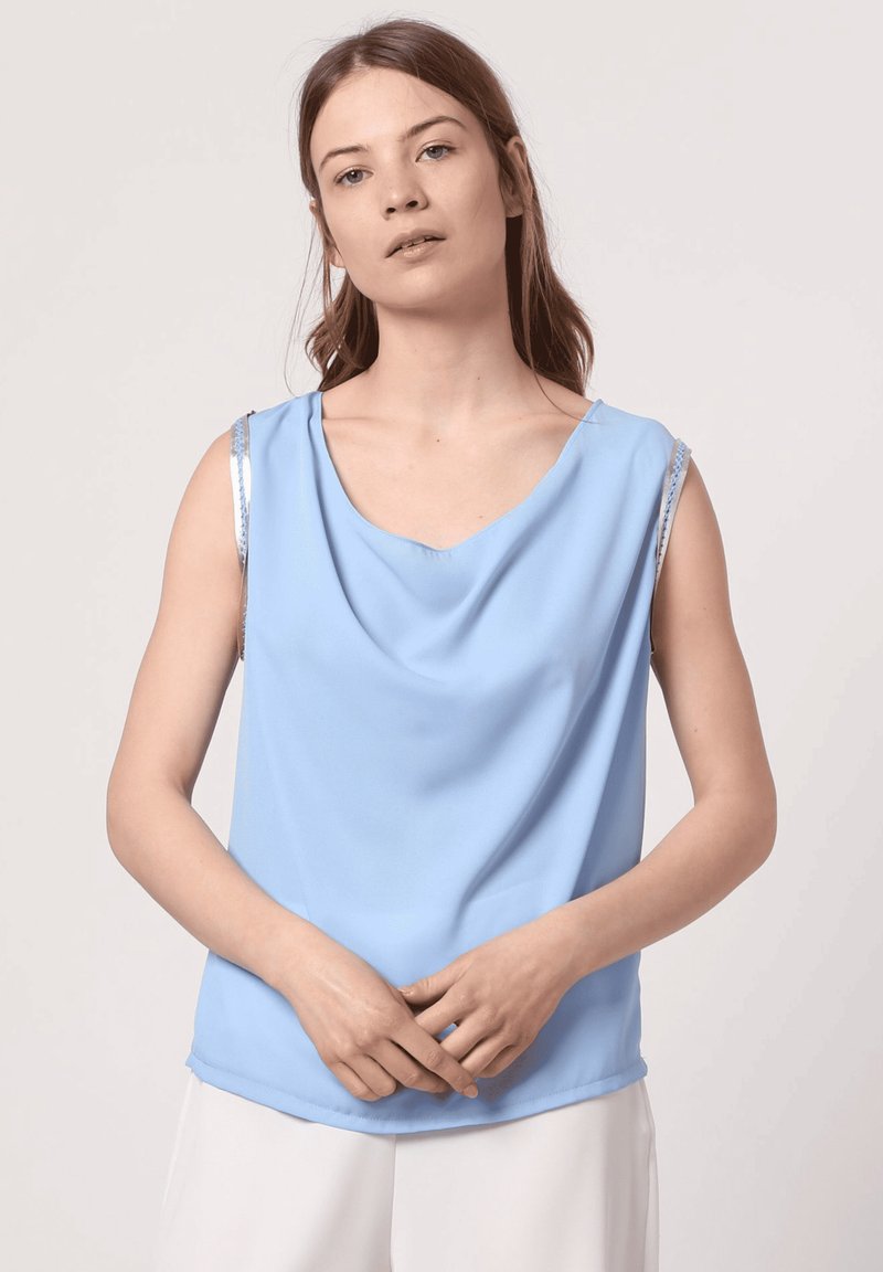 Top azul sin mangas hecho de una tela suave, con un escote drapeado y acentos plateados en los hombros. Diseño simple y elegante.