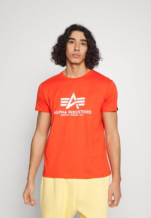 Rotes Baumwoll-T-Shirt mit einem auffälligen weißen "ALPHA INDUSTRIES"-Logo, rundem Halsausschnitt und kurzen Ärmeln. Glatte Textur mit lässigem Schnitt.