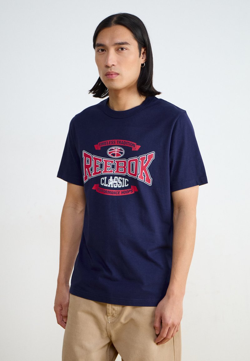 Mørkeblå bomulls T-skjorte med et fremtredende rødt og hvitt "Reebok Classic" grafikk, korte ermer og rund hals.