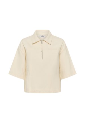 Kremno obarvana majica s kratkimi rokavi, ovratnikom in sprednjim polovičnim zadrgo, z ohlapnim krojem in spuščenimi šivi ramen.