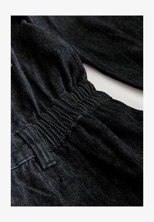 Zwarte denimstof met een zachte textuur en een lichte stretch. Kenmerkt zich door een geraffineerde tailleband, accentueerde naden en een casual ontwerp.