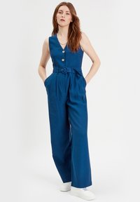 Jumpsuit blu senza maniche con scollatura a V, chiusura a bottoni, cintura in evidenza, tasche laterali e gambe ampie, realizzato in un tessuto liscio.