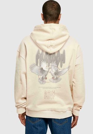 Cream hoodie with a large graphic featuring two doves and the word "FREEDOM" on the back. Soft fabric with a relaxed fit and drawstring hood.