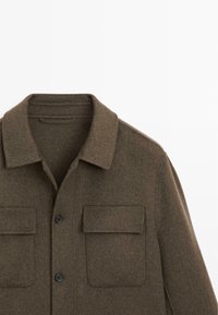 Braune Wollhemdjacke mit klassischem Kragen, zwei Brusttaschen und schwarzen Knöpfen. Weiche Textur und geradlinige Silhouette.