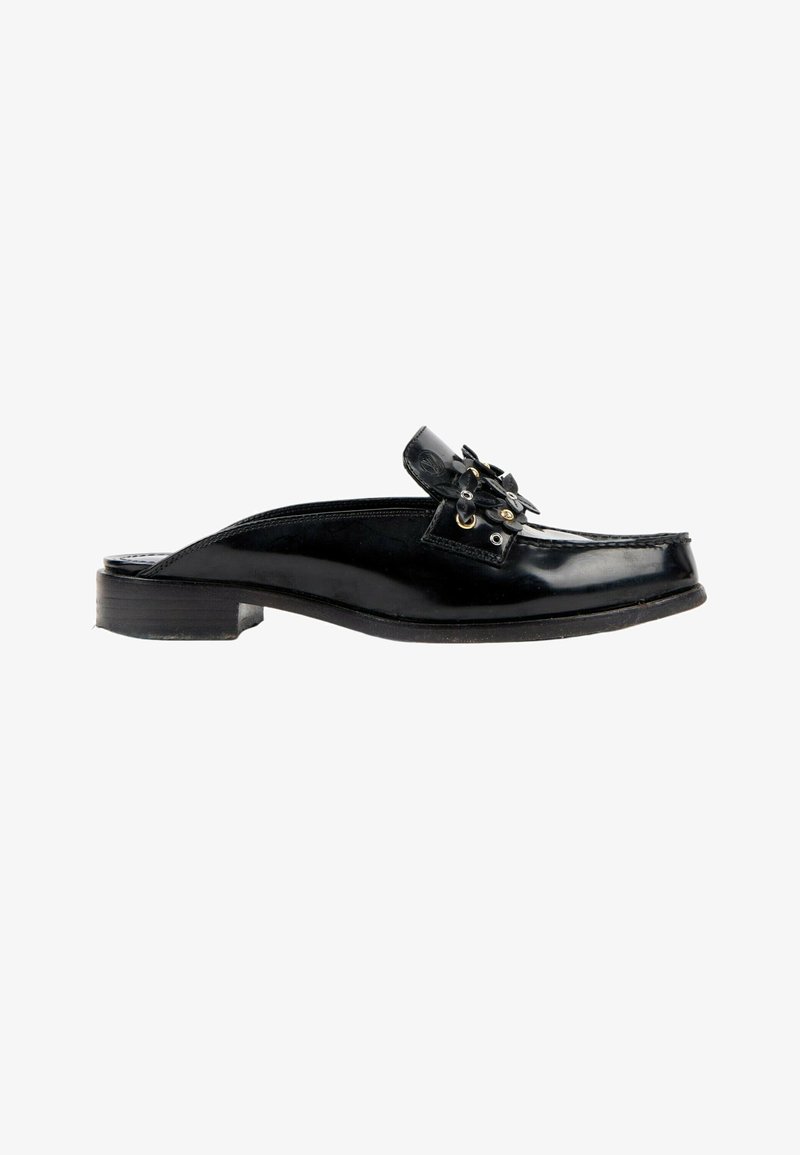 Chaussure en cuir noir à enfiler avec un petit talon et une fleur noire décorative ainsi que des œillets dorés sur le dessus.