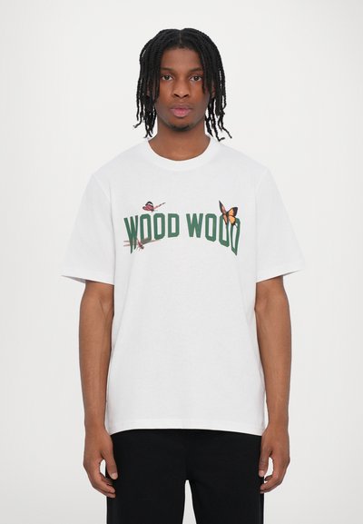 Fehér pamut póló zöld "WOOD WOOD" felirattal és pillangó grafikákkal. Rövid ujjú, kerek nyakkivágású és laza szabású.