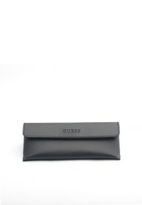 Funda de cuero negro con un acabado texturizado, que presenta un cierre con solapa y el logo en relieve "GUESS" en la parte frontal. Forma rectangular.