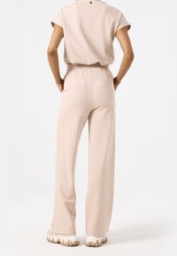 Beige, stickad tvådelad set med en avslappnad, kortärmad topp och vida byxor med elastisk midja och bakfickor. Texturerad tyg.