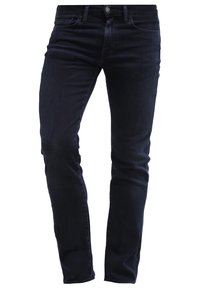 Jean en denim bleu foncé à coupe slim, doté de cinq poches, d'une fermeture à boutons et d'une ceinture régulière. Texture lisse et design épuré.