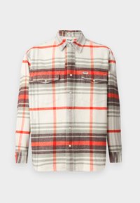 Camisa de cuadros en beige, rojo, gris y blanco. Manga larga, con cierre de botones en el frente, dos bolsillos en el pecho y una etiqueta de Wrangler en el bolsillo izquierdo.