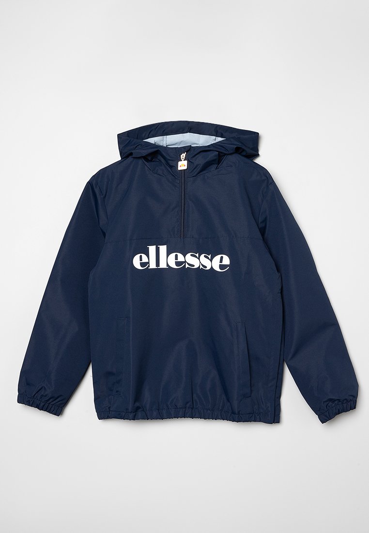 Chaqueta cortavientos azul marino con capucha, media cremallera, puños elásticos y dos bolsillos laterales; presenta un gran logo blanco de "ellesse" en la parte frontal.