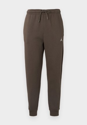 Bruna sweatpants i mjukt material med elastiskt midjeband och snörning samt en vit logotyp på vänster lår. Snäva muddar.