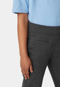 Camisa polo de manga corta azul claro combinada con pantalones de textura suave en gris oscuro que cuentan con un bolsillo lateral y una cintura ajustada.
