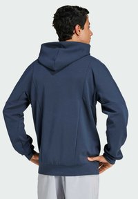 Sweatshirt à capuche bleu marine avec une coupe décontractée, des manches longues, des détails sur les coutures latérales et un ourlet côtelé, fabriqué à partir d'un tissu doux et lisse.