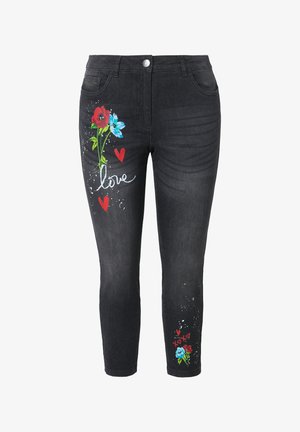 Schwarze Skinny-Jeans mit roten und blauen Blumenmustern, die Herzen und das Wort "Liebe" in Weiß zeigen. Hergestellt aus Denim mit einer glatten Textur.
