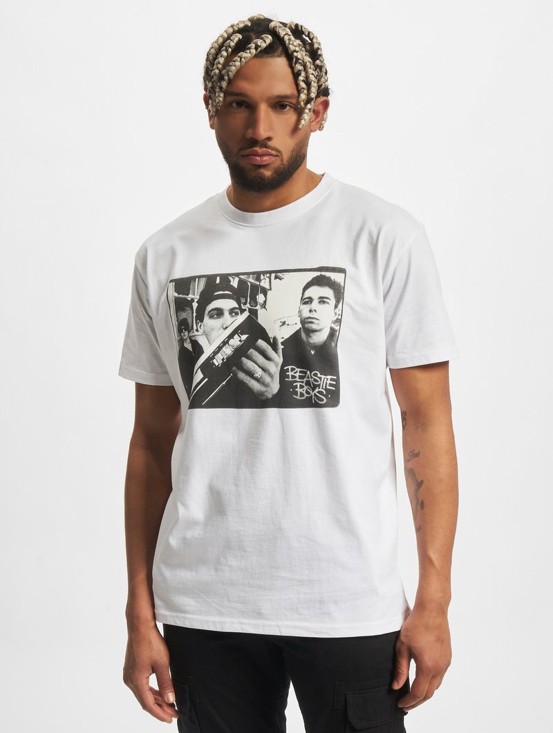 Fehér pamut póló, melyen fekete-fehér grafikai nyomat látható két személlyel, alatta "BEASTIE BOYS" felirattal. Kerek nyak, rövid ujjak.