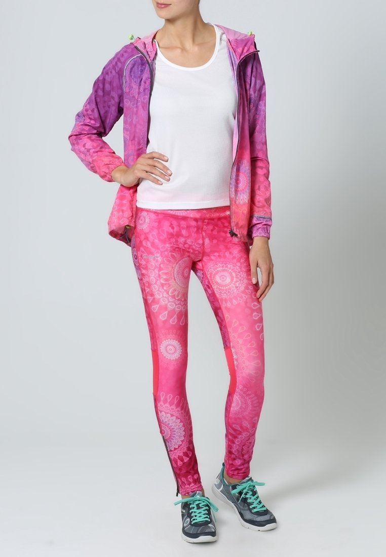 Completo da attrezzatura attiva che presenta una giacca leggera con zip dai colori degradé viola a rosa; leggings aderenti con un motivo mandala in tonalità di rosa.