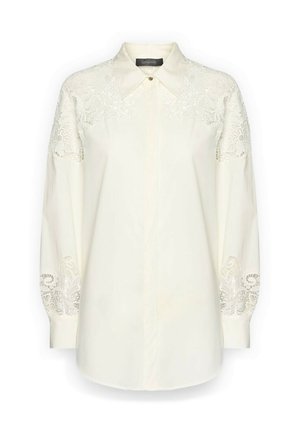 Crèmewitte blouse met lange mouwen, kantdetails op de schouders en manchetten, puntige kraag en verborgen knopen aan de voorkant.