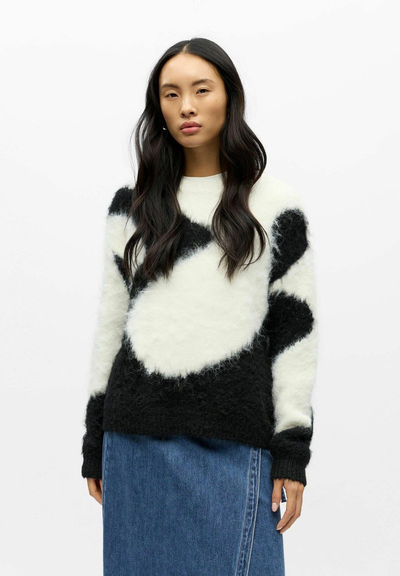 Svart og hvit, lodden genser med abstrakt mønster, rund hals og lange ermer. Brukes med denimskjørt. Mykt, teksturert stoff.