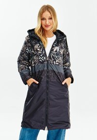 Pohodlný námořnický kabát s květinovým potiskem v horní části, se zapínáním na zip a kapucí. Obsahuje dvě přední kapsy a texturovaný panel ve střední části.