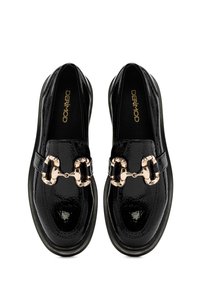 Schwarze Lacklederloafers mit einem dekorativen goldenen Kettenakzent, abgerundeter Zehenpartie und schwarzer Gummisohle mit Nahtdetails.