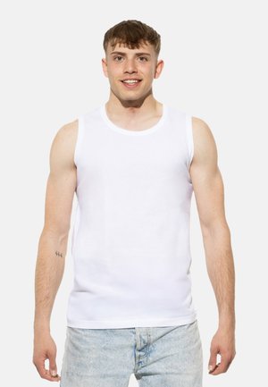 Débardeur blanc en coton, avec un col rond et sans manches. Porté avec un jean en denim bleu clair.