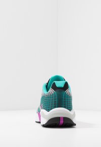 Sneaker med ovandel i mesh i teal och svart, med ett rutmönster, en vadderad krage och en vit sula med lila accent.