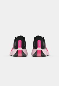 Chaussures de sport noires et roses avec une tige en maille texturée, un collar rembourré, un talon prononcé et une semelle extérieure en caoutchouc à motifs.